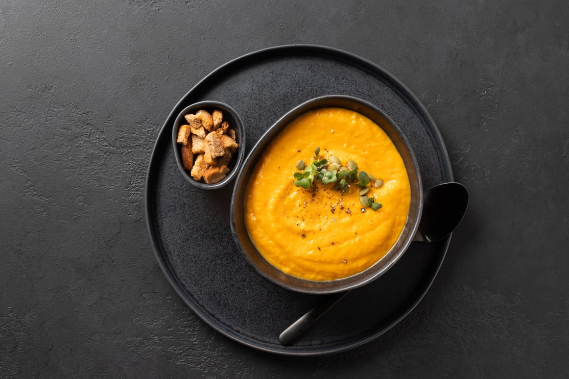 Pumpkin soup garnish microgreens on black. Top view.